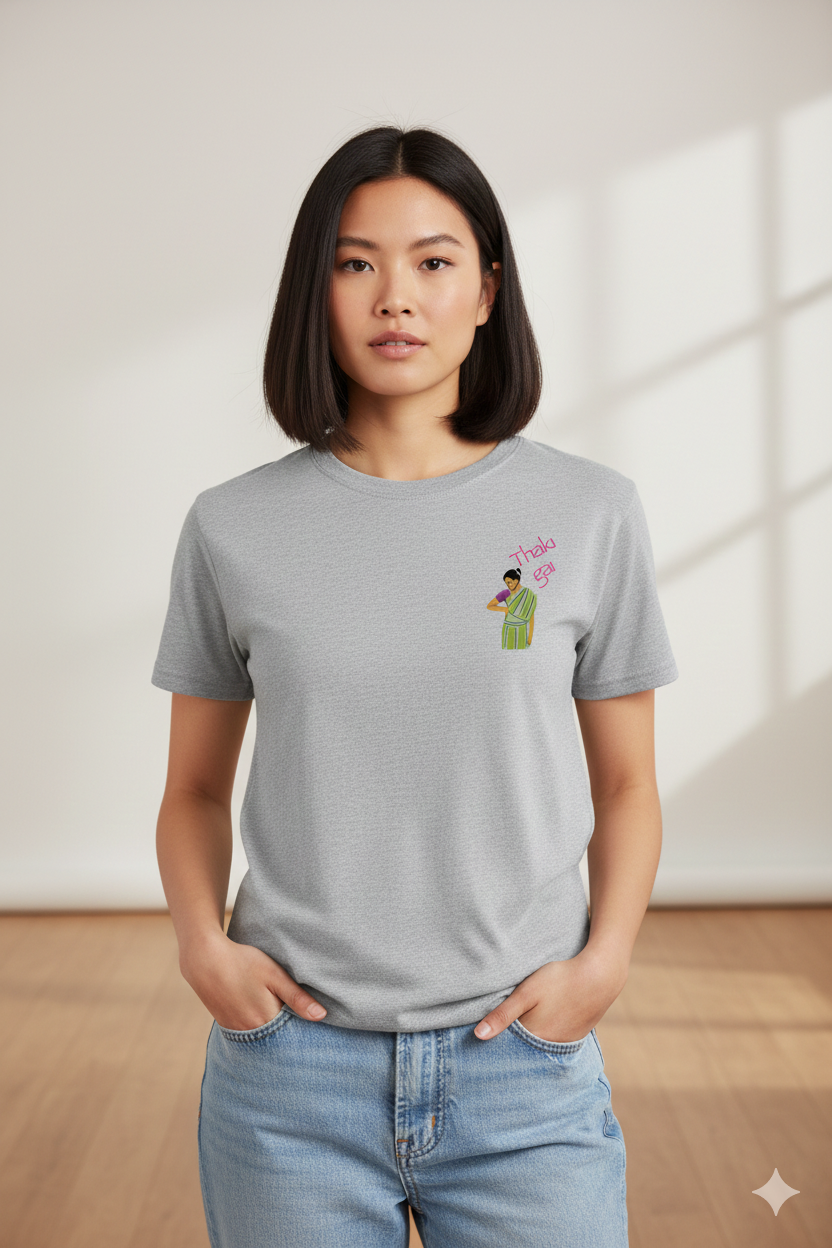 Woman wearing a grey t-shirt with a Thaki Gai graphic design on left chest